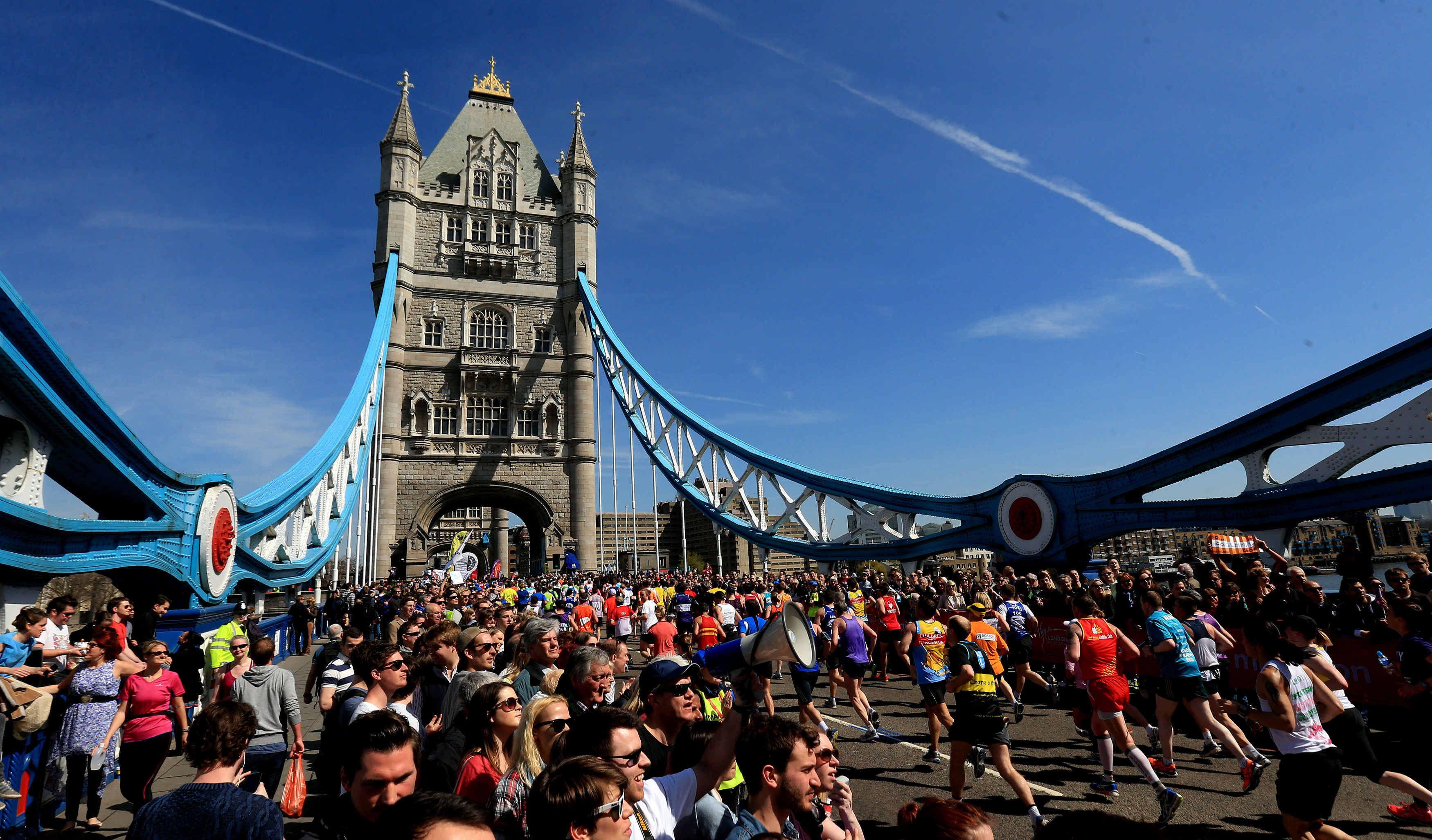 Spectators watch as runners cross Tower Bridge during the Virgin London Marathon in London.